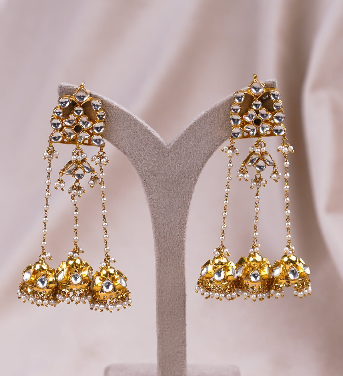 Elegant gold jhumka earrings with pearl drops and kundan stones, perfect for traditional Indian weddings and festive occasions.