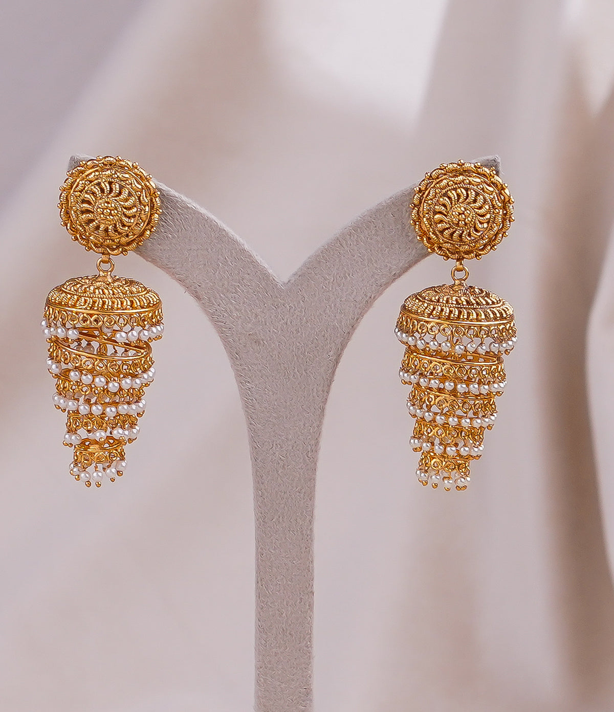 Elegant gold jhumka earrings with pearl detailing, perfect for traditional occasions.