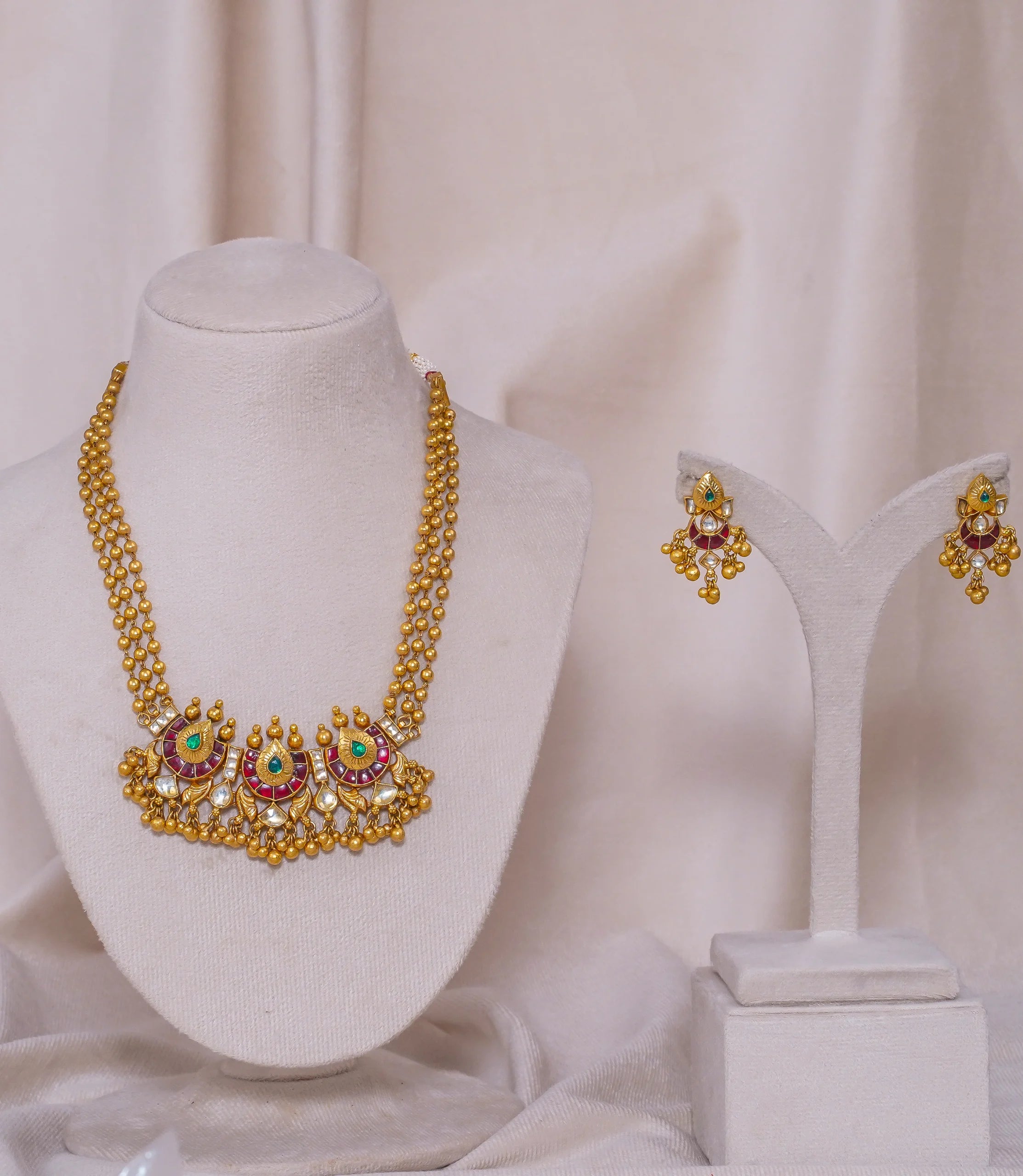 Elegant gold necklace and earrings set with red and green gemstones, perfect for traditional occasions.
