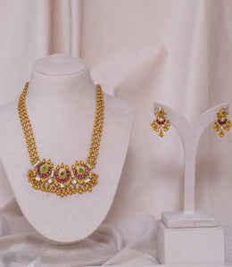 Elegant gold necklace and earrings set with red and green gemstones, perfect for traditional occasions.