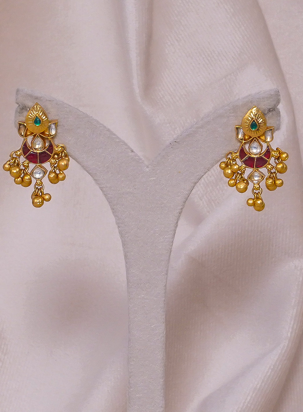 Gold jhumka earrings with red and green gemstones, traditional Indian jewelry design