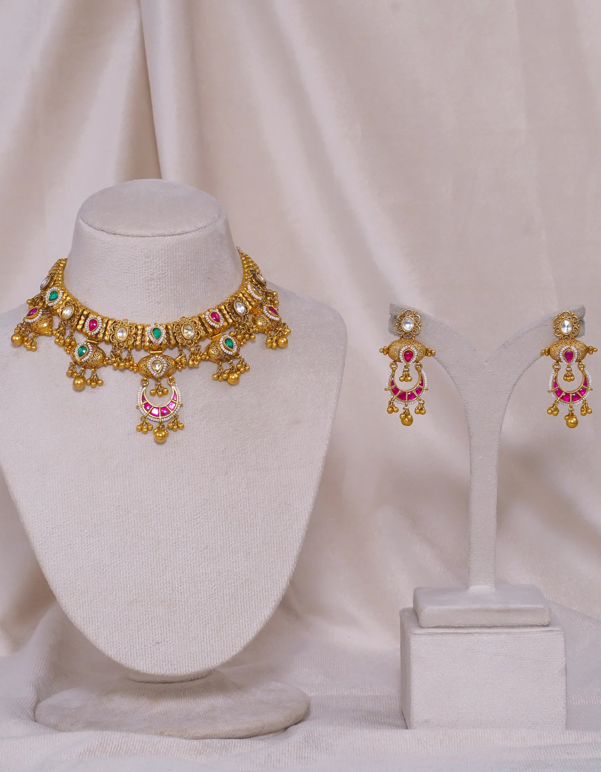 Gold necklace and earrings set with pink and green gemstones, traditional Indian jewelry design