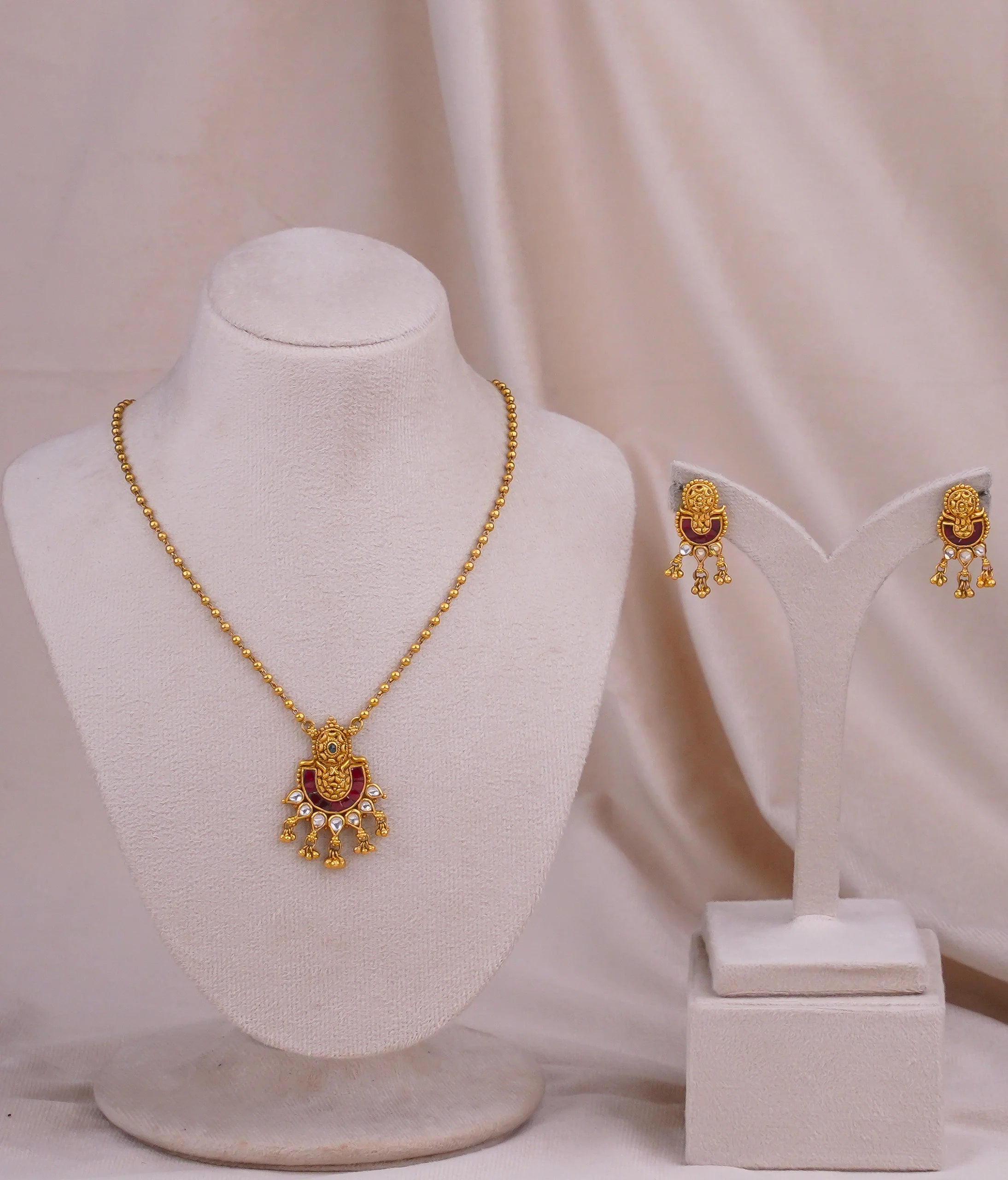 Gold necklace and earrings set with red and white gemstones, traditional Indian jewelry design