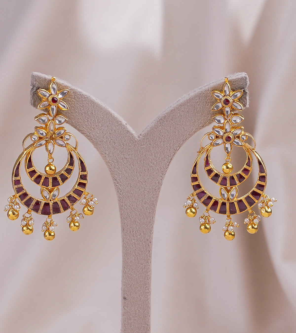 Elegant gold earrings with red and white gemstones, floral design, and dangling beads