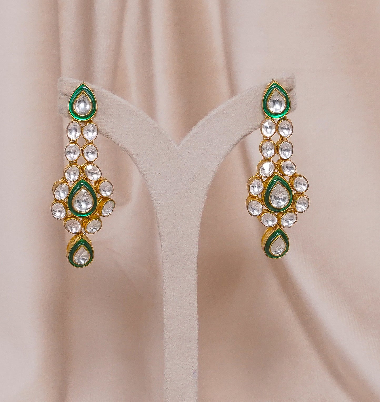Elegant gold earrings with green enamel and clear gemstones, perfect for festive occasions.