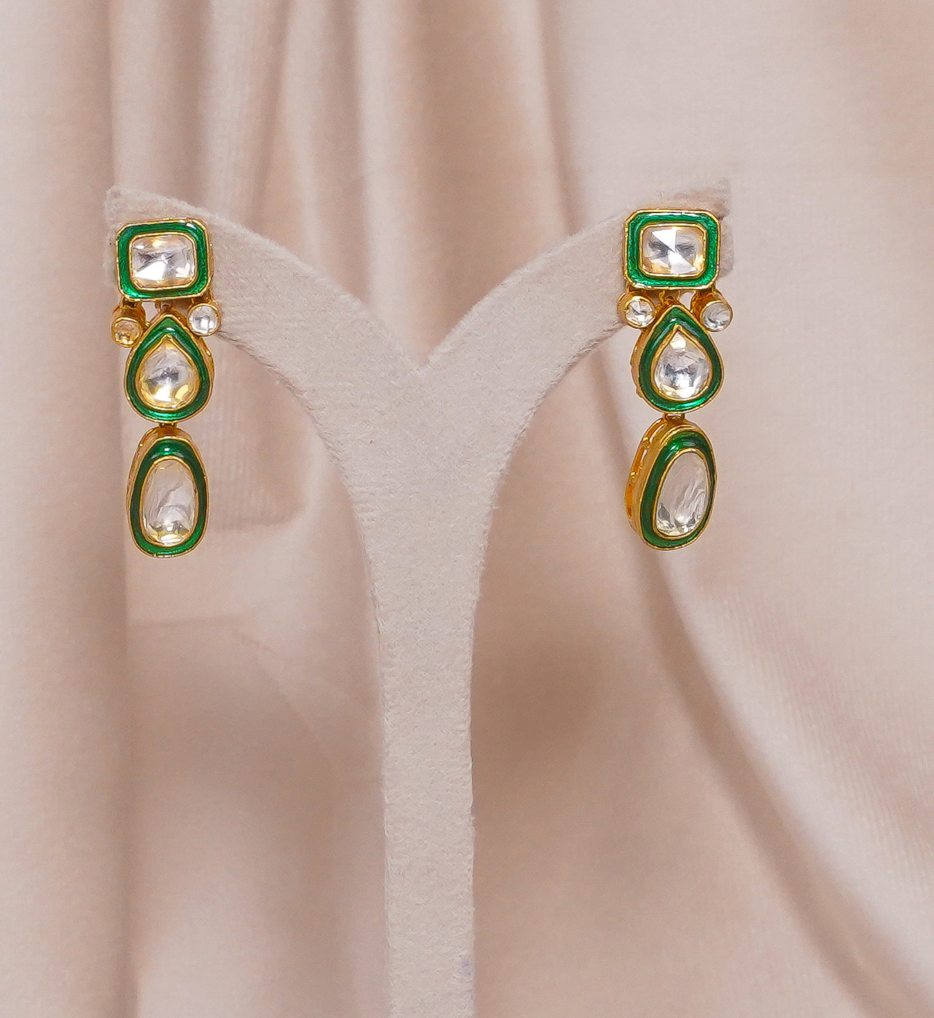 Gold kundan earrings with green enamel and white stones, traditional Indian jewelry design