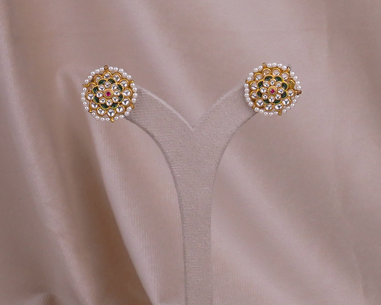 Elegant gold earrings with pearls and gemstones on soft fabric