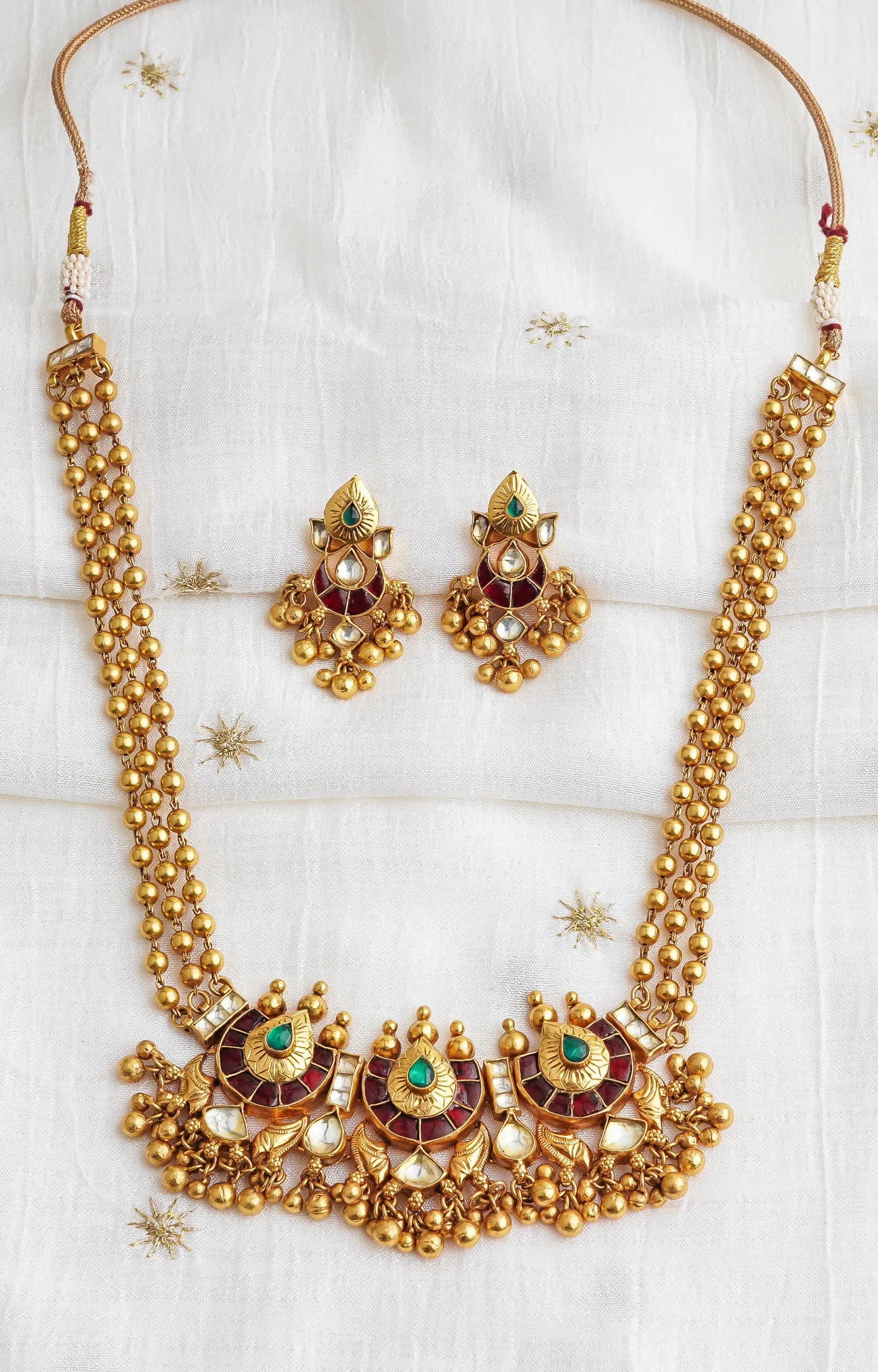 Elegant gold necklace and earrings set with emerald and ruby accents, perfect for traditional occasions.