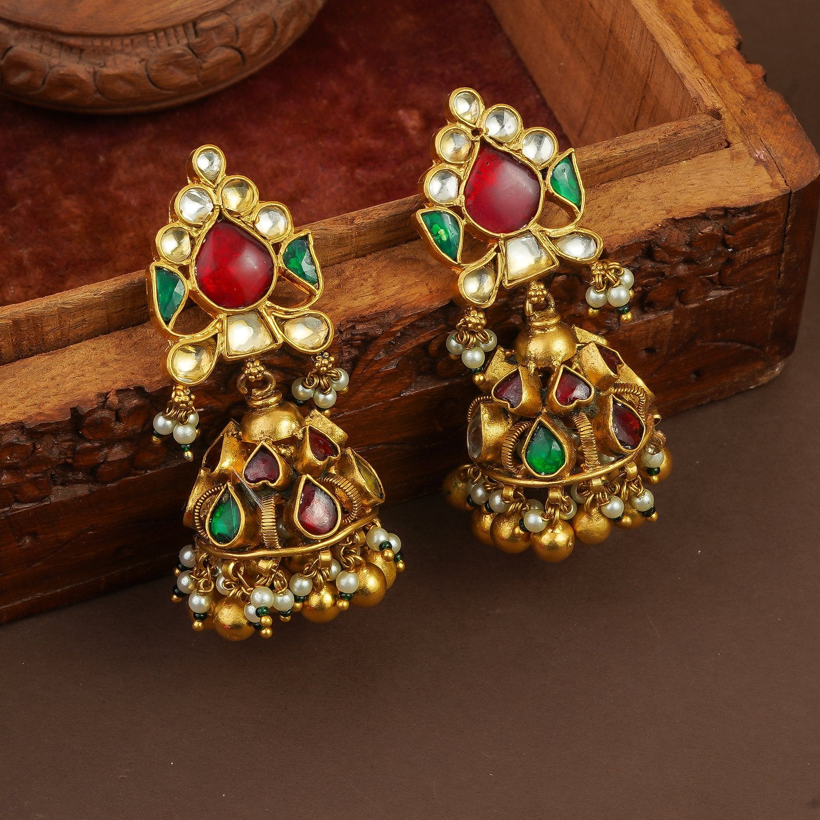 Gold jhumka earrings with red and green gemstones, pearl accents, and intricate detailing