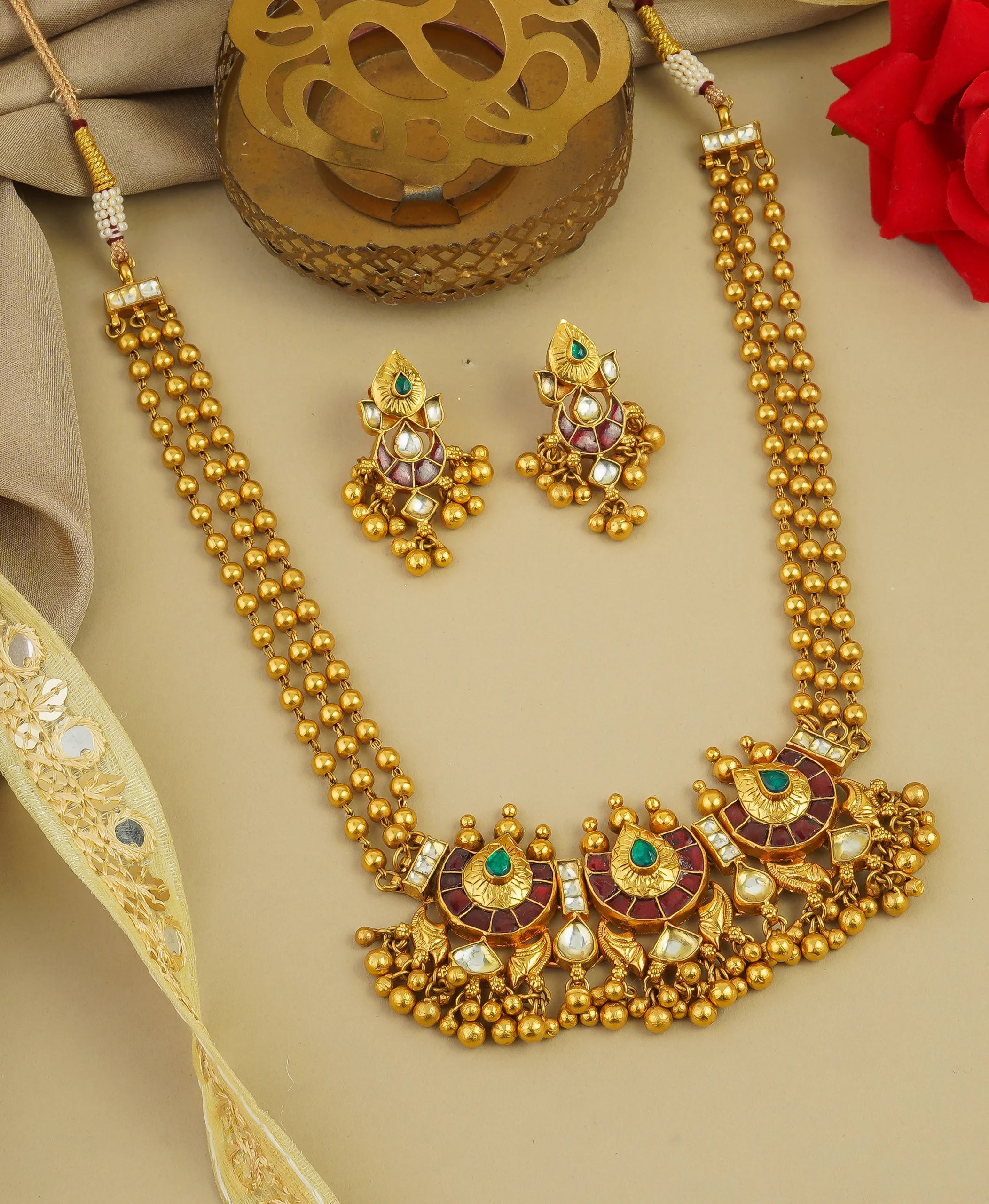 Elegant gold necklace and earrings set with emerald and ruby accents, perfect for traditional occasions.