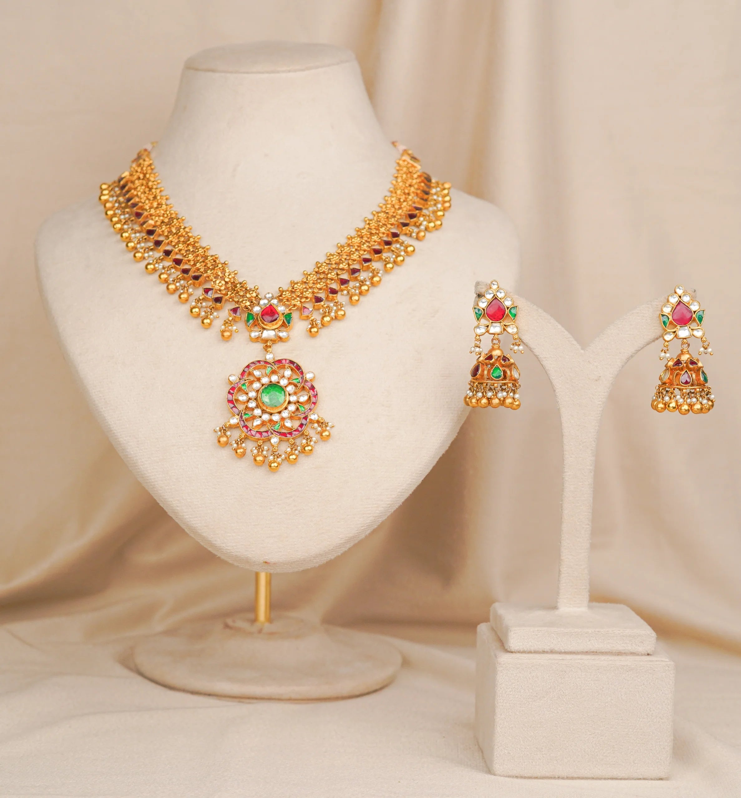 Gold necklace set with red green stones and matching jhumka earrings, traditional Indian bridal jewelry