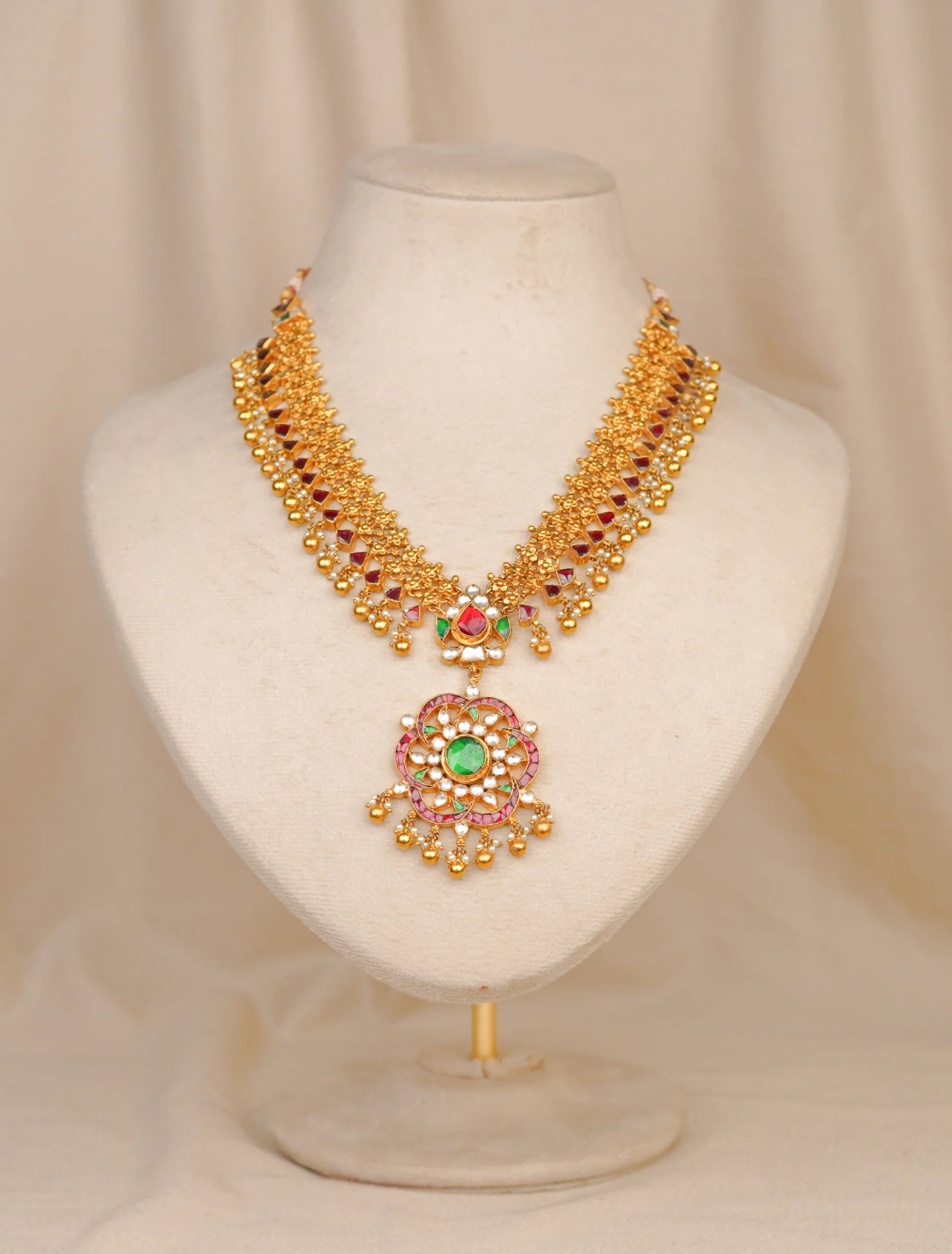 Elegant gold necklace with green and red gemstones, perfect for traditional occasions.