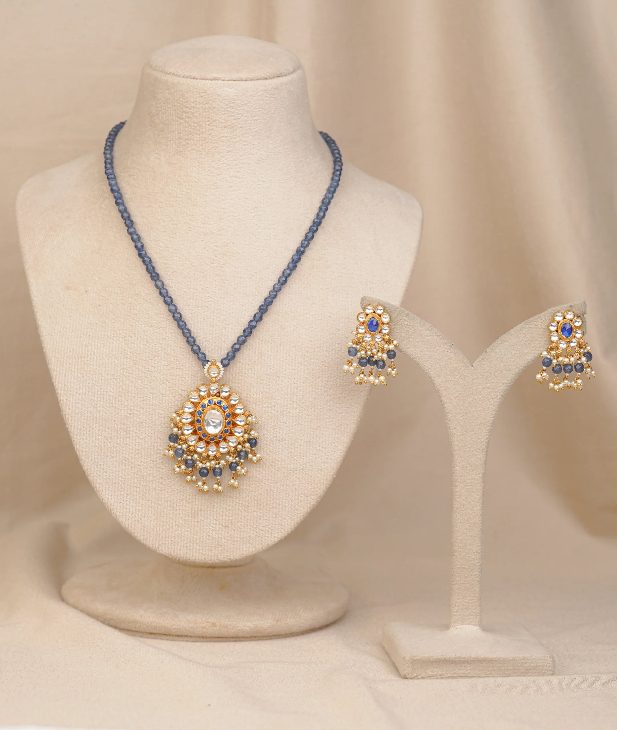 Elegant gold necklace set with blue beads, kundan pendant, and matching earrings for women