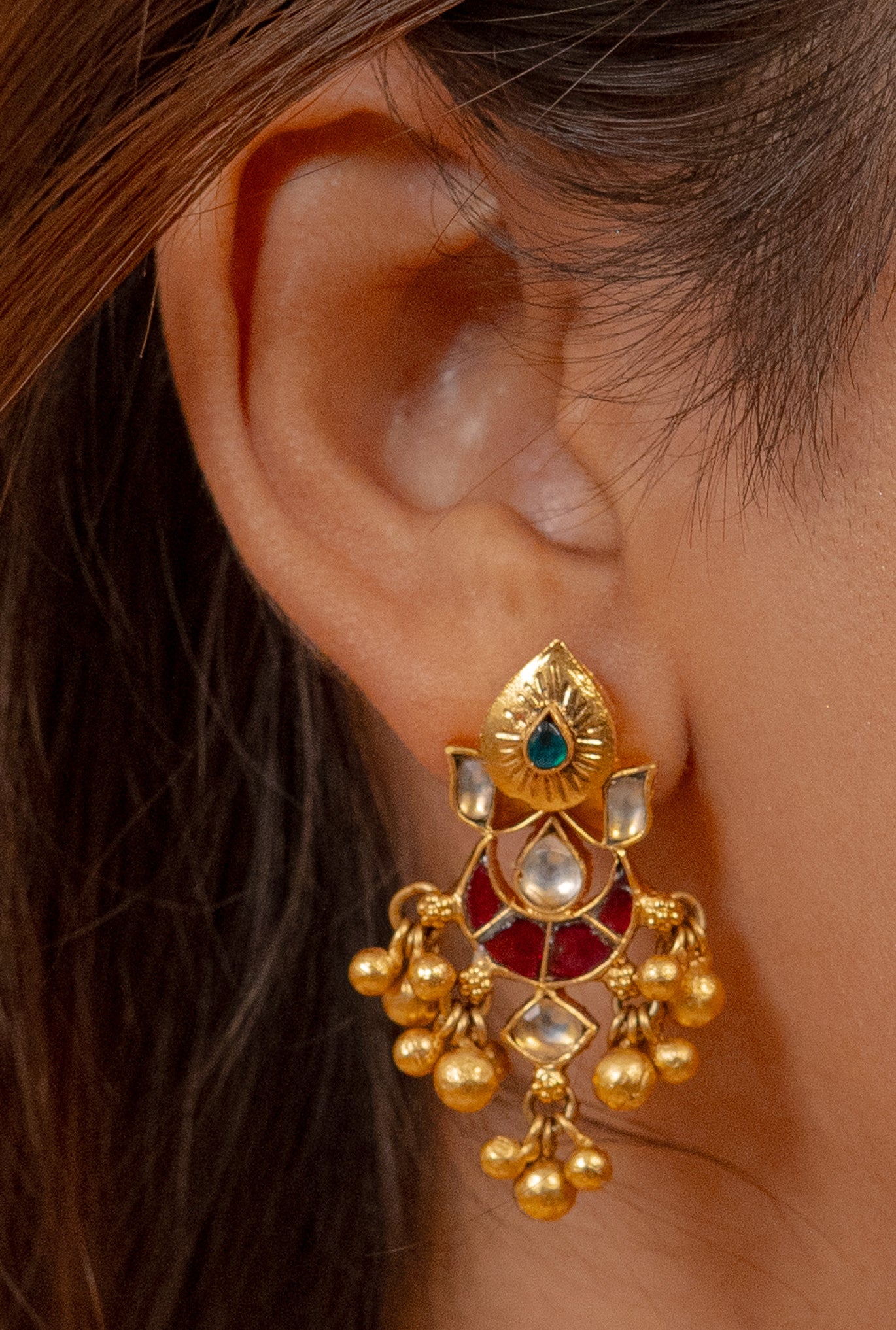 Gold jhumka earring with emerald and red enamel, traditional Indian jewelry design