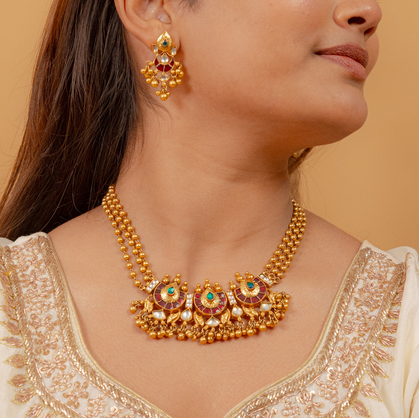 Elegant gold necklace and earrings set with red and green gemstones, perfect for traditional wear.